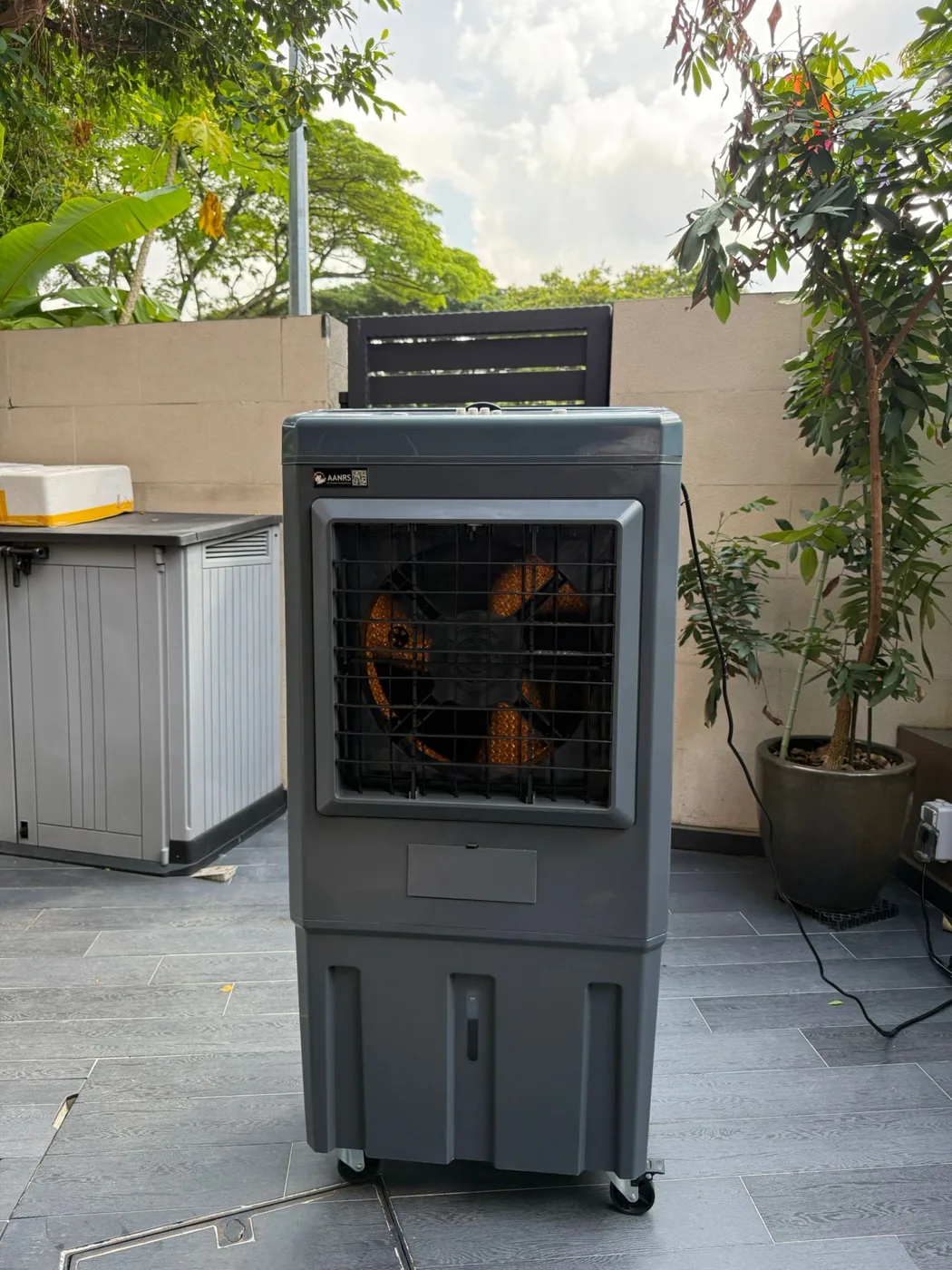 AANRS air cooler rental Singapore, mobile evaporative air cooler standing on a tiled outdoor patio beside potted plants