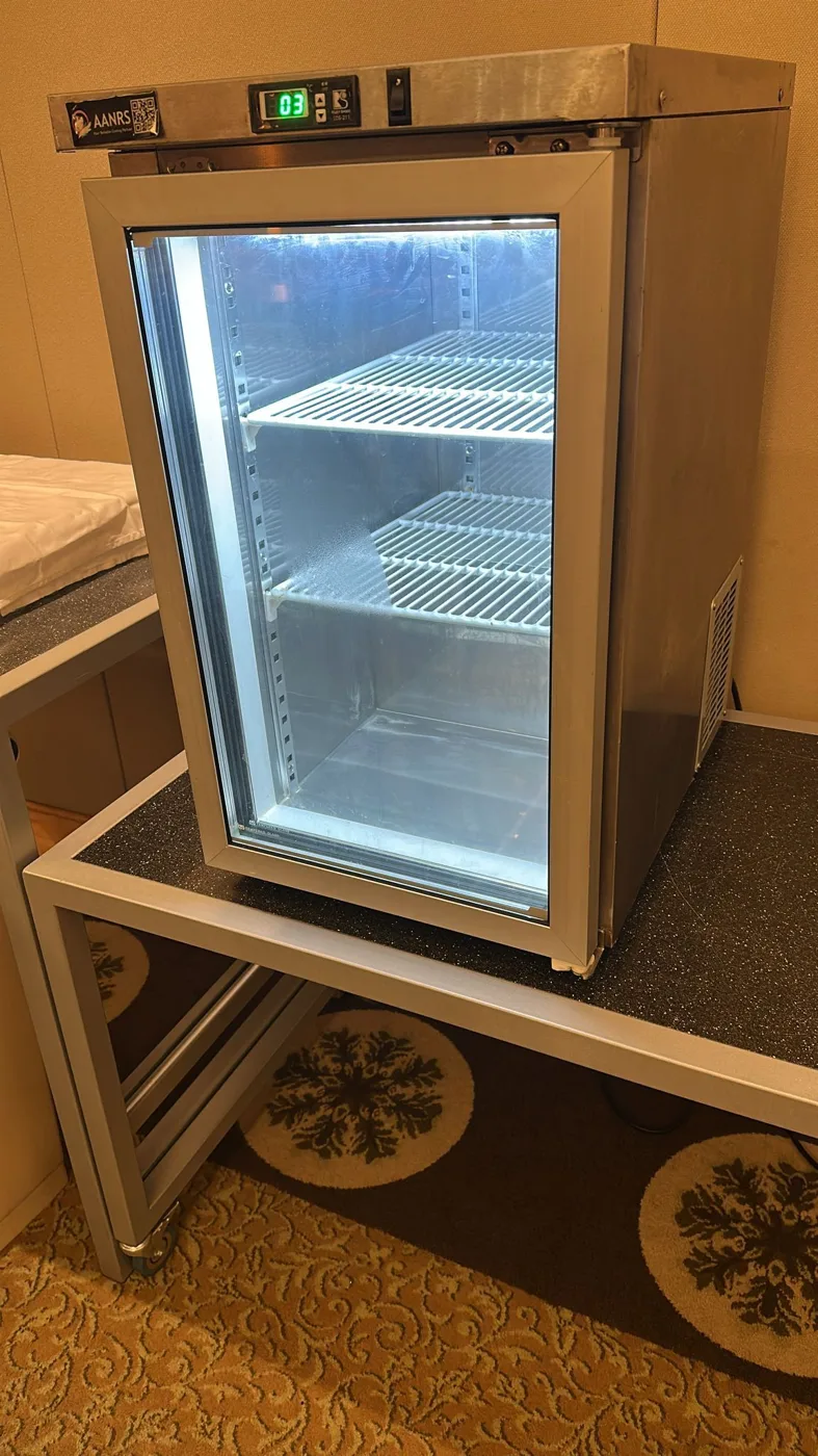 AANRS undercounter chiller rental Singapore, small stainless glass-door chiller sitting on a stand in a carpeted hotel function room